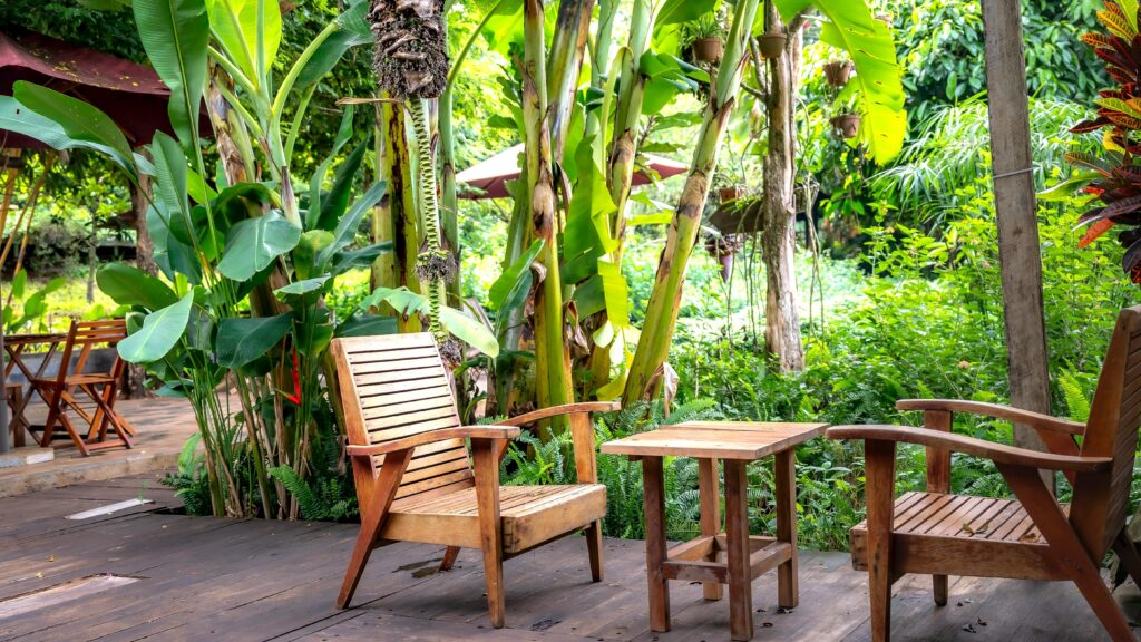 A cozy garden seating area with a wooden bench surrounded by potted plants and greenery