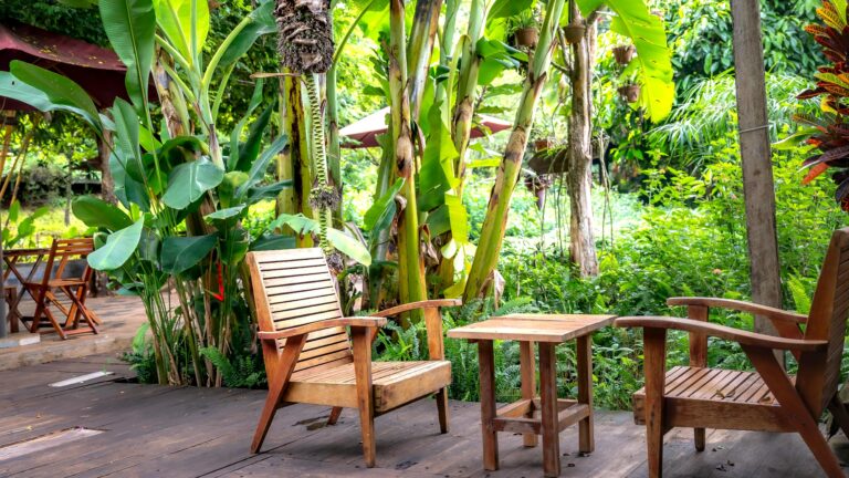 A cozy garden seating area with a wooden bench surrounded by potted plants and greenery